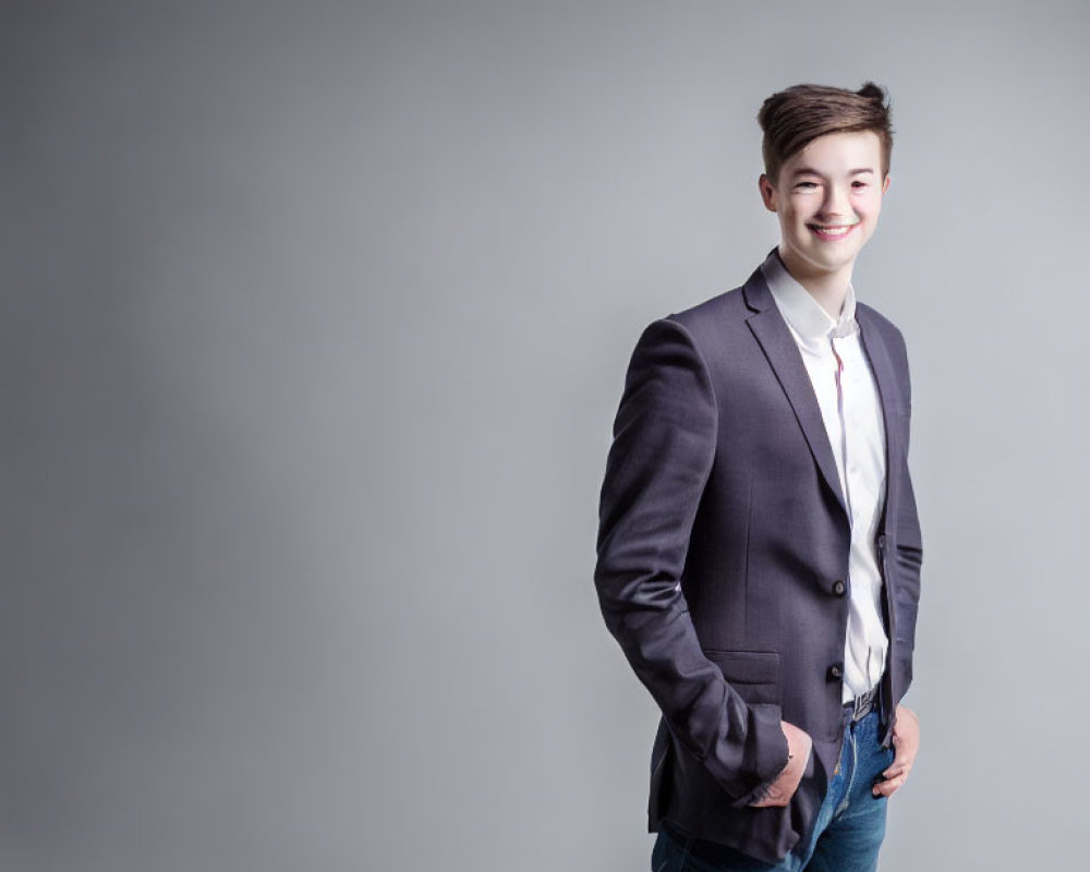 Smiling young man in semi-formal attire against grey background