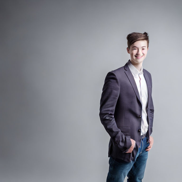 Smiling young man in semi-formal attire against grey background