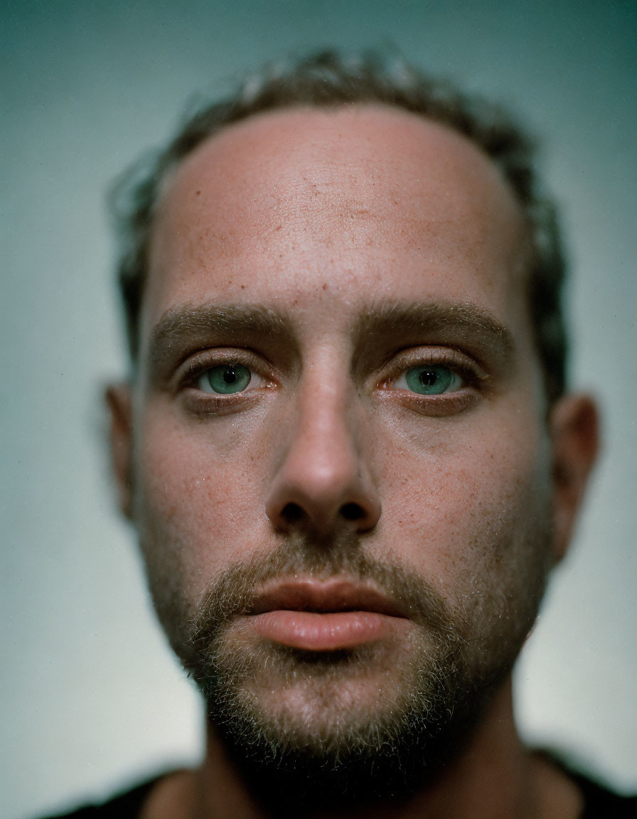 Intense gaze man with stubble and green eyes portrait.