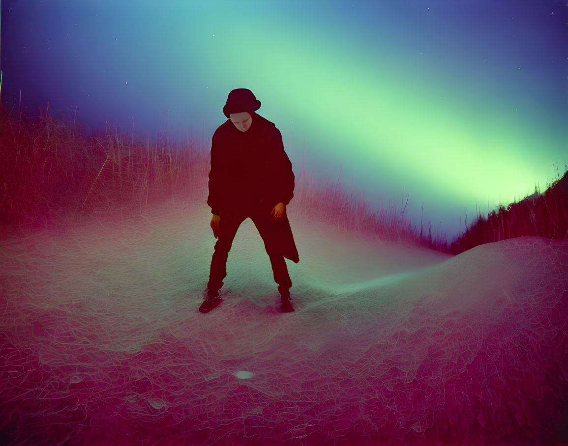 Mysterious figure in hat and coat under green aurora sky