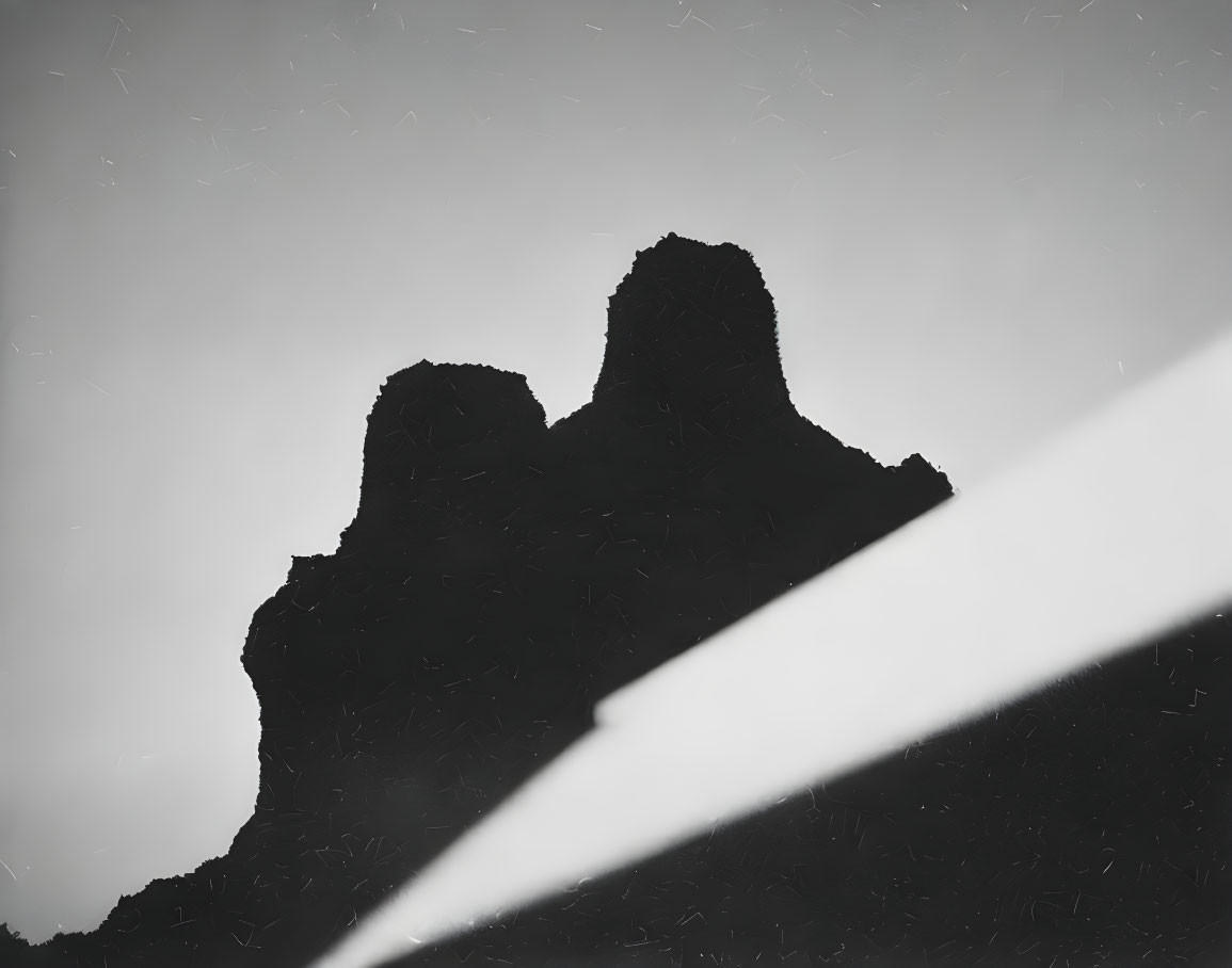 Jagged Mountain Peaks Silhouette on Weathered Gray Sky Background