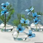 Blue Flowers in White Vases on Table with Petals and Empty Vases