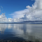 Abstract seascape painting with blue and white layers depicting sky, clouds, calm sea, land, and