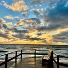 Person on Wooden Pier at Sunrise with Orange Clouds Reflection