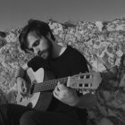 Monochromatic artwork of man playing guitar in desolate landscape