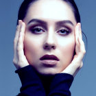 Surreal portrait of pale-skinned female with golden lips and eyes on blue background