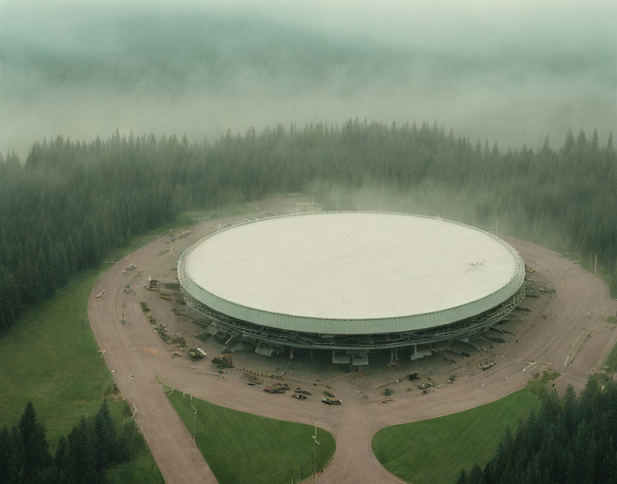 Circular white building in forest with fog - Aerial view