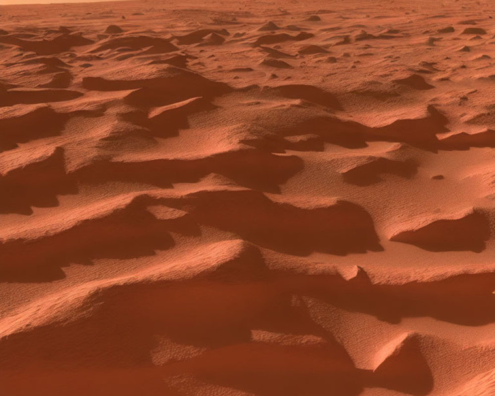 Reddish Martian terrain with windswept dunes under a hazy sky