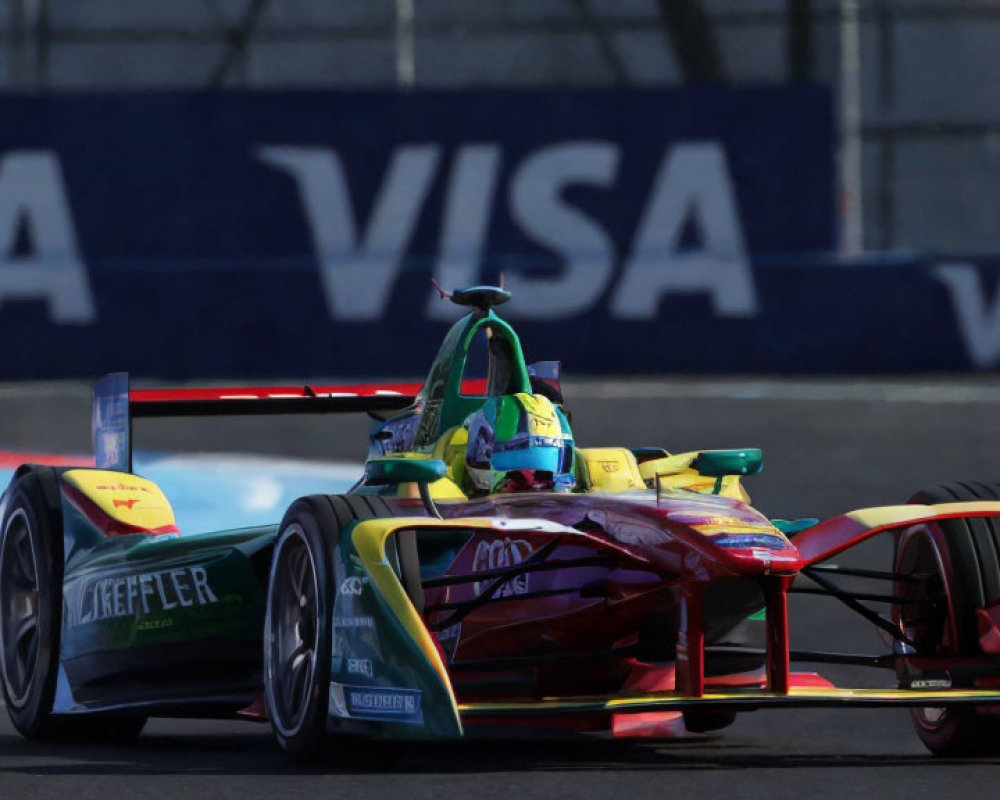 Vibrant Formula E race car on track with tire barriers and sponsorship banners