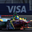 Vibrant Formula E race car on track with tire barriers and sponsorship banners