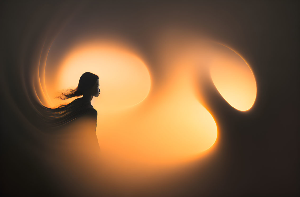 Silhouette of woman with flowing hair on warm abstract background