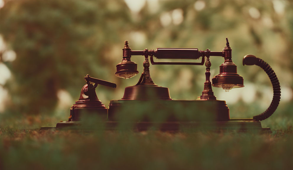 Vintage rotary dial telephone on grass with blurred green background