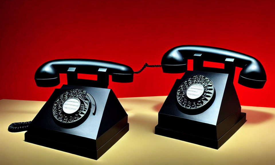 Vintage Black Rotary Phones Connected by Cord on Red Background