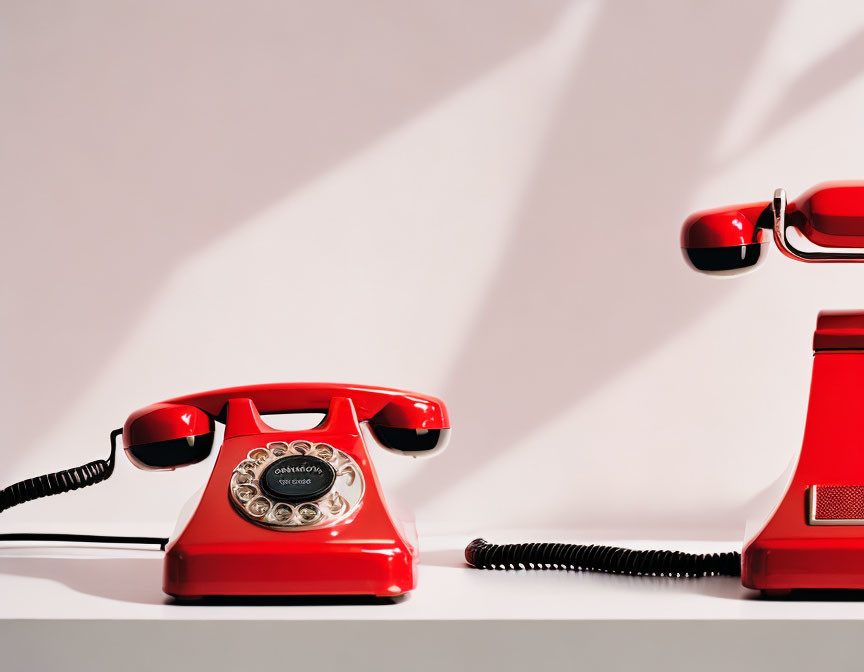 Vintage Red Rotary Telephone with Handset Off Hook on Light Background