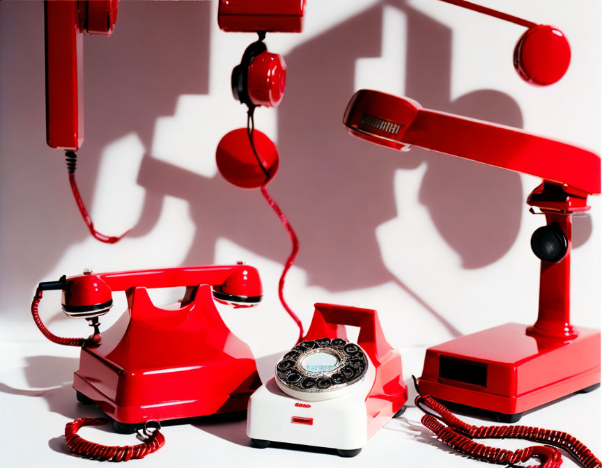 Vintage Red Telephones with Off-Hook Handsets on White Background