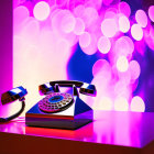 Vintage Rotary Telephone with Pink and Purple Lighting on Bokeh Background