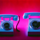 Vintage Aqua and Pink Rotary Phones on Red Background with Handsets Off-Hook