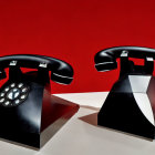 Vintage Rotary Dial Telephones with Lifted Handsets on Red Background