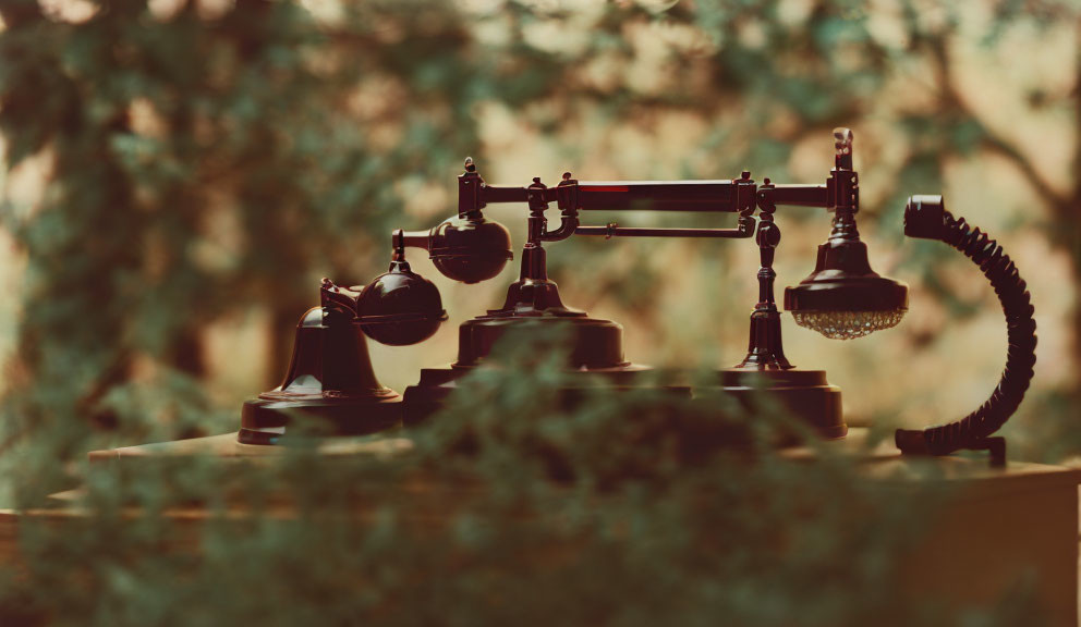 Vintage Telephone on Desk with Green Foliage Background