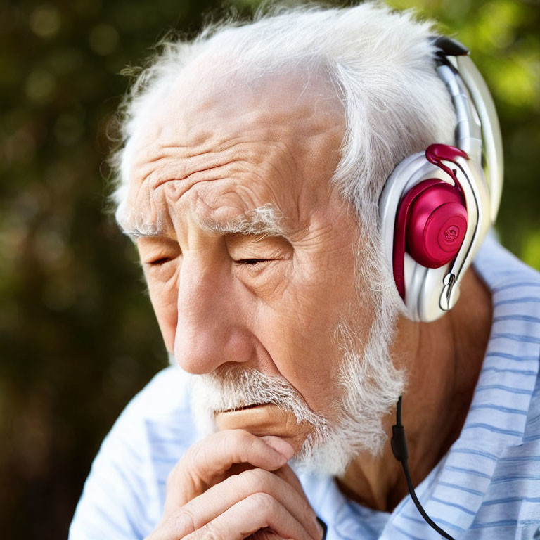 Senior man with beard in headphones, eyes closed, contemplating nature background