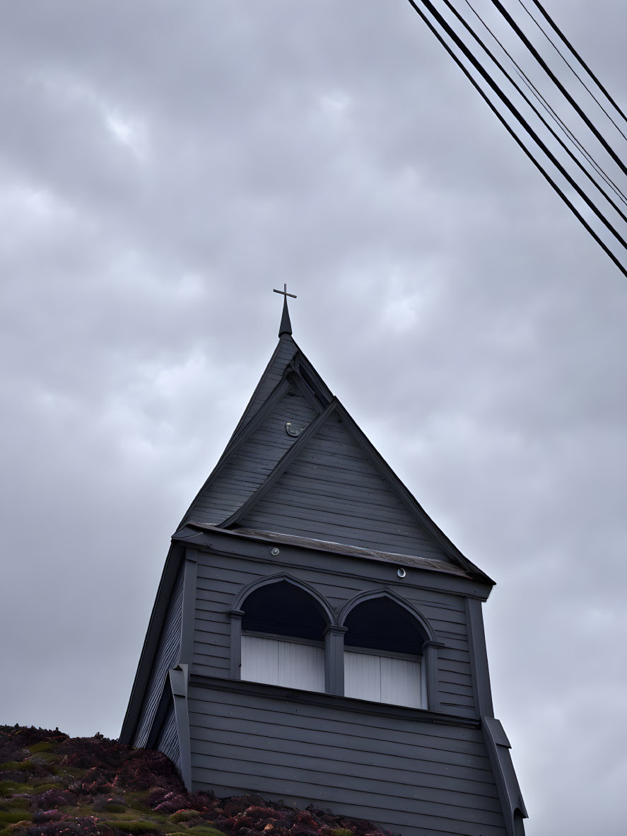 Wooden Church Steeple and Cross Under Overcast Sky with Power Lines and Hillside