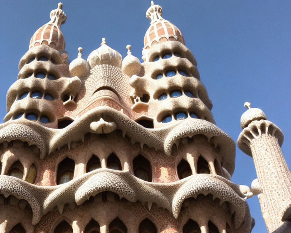 Organic-shaped architectural structure with elaborate chimneys under clear blue sky