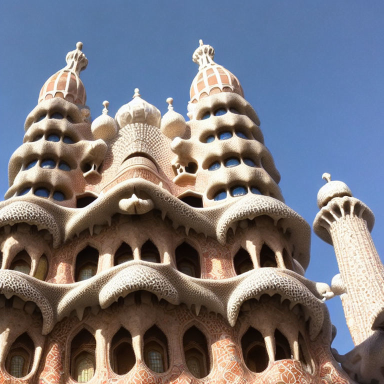 Organic-shaped architectural structure with elaborate chimneys under clear blue sky