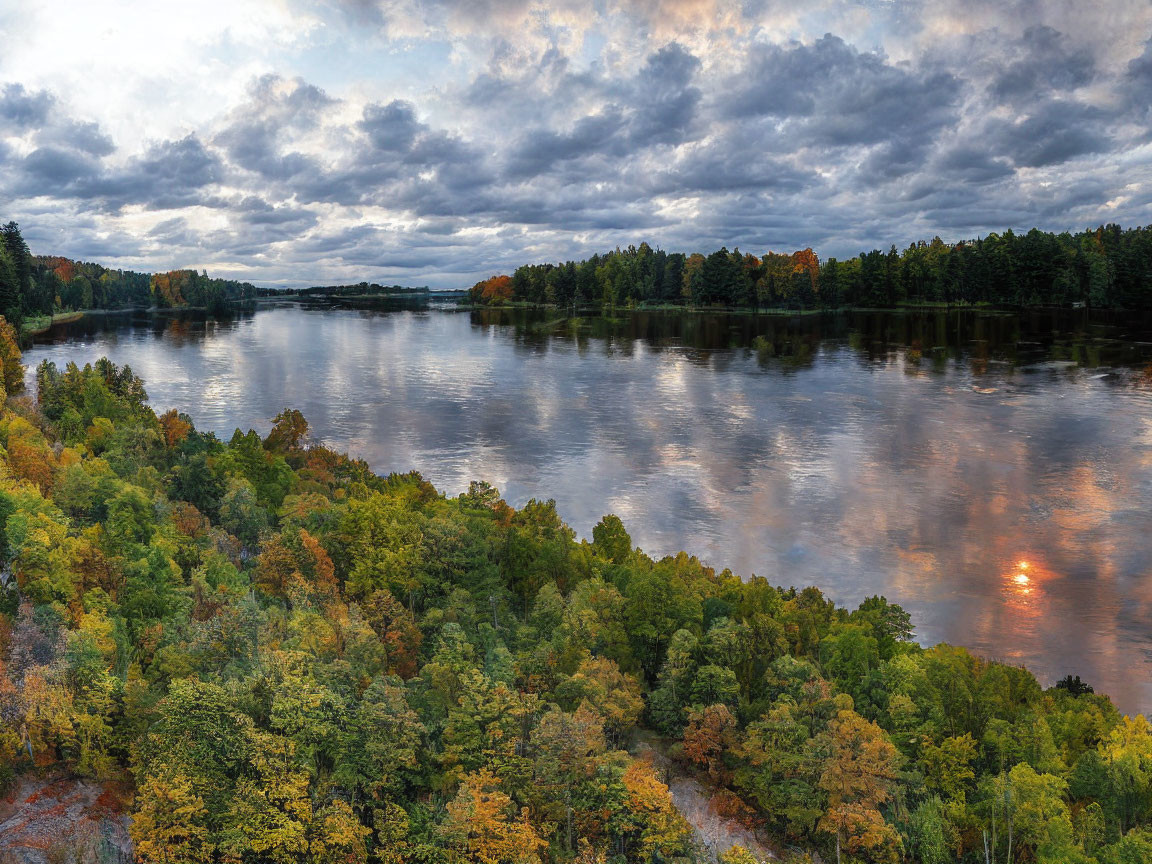 Tranquil river mirroring cloudy sky and autumnal forests