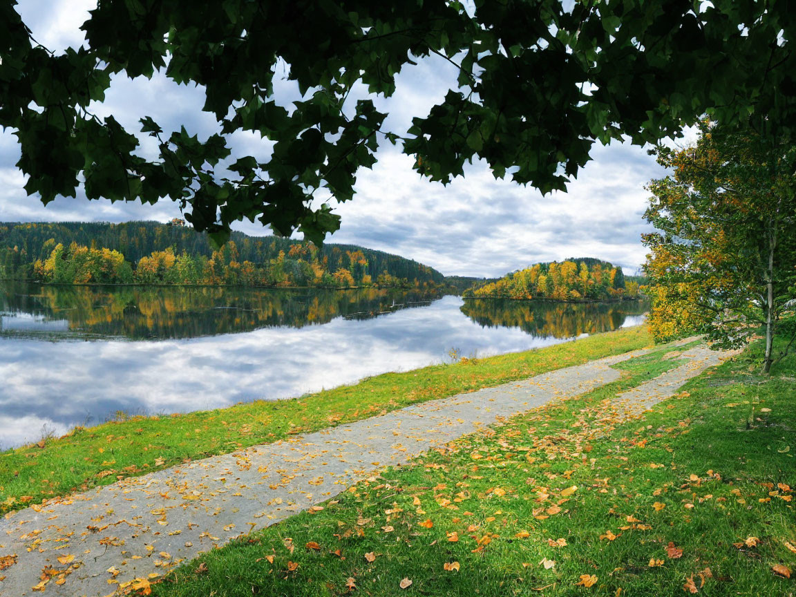 Autumn riverside landscape with reflections, footpath, leaves, and green foliage