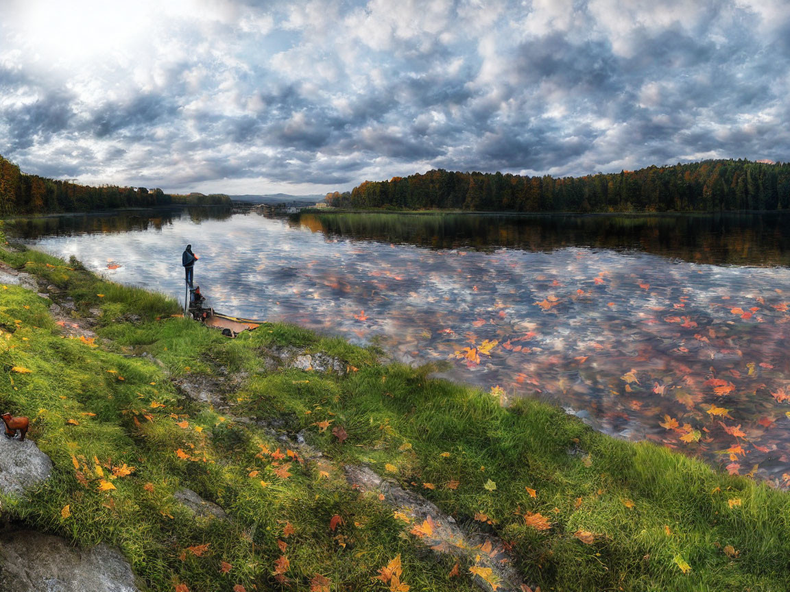 Person fishing by serene river with autumn leaves and dramatic sky.