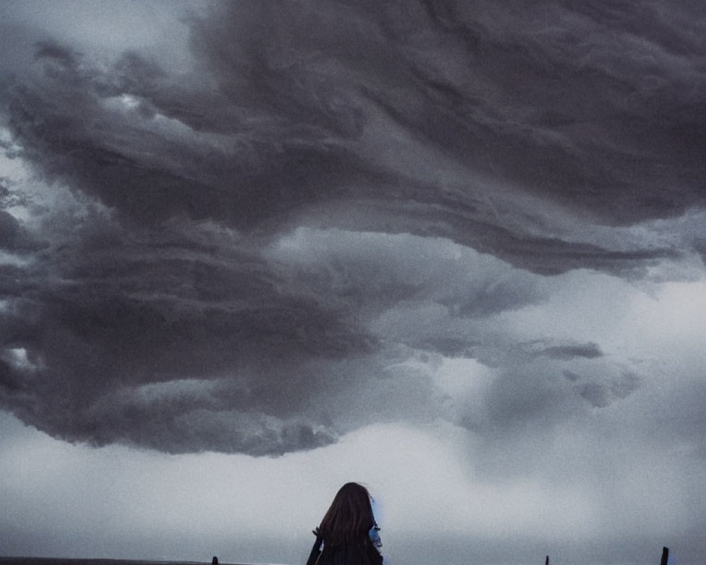 Solitary figure under stormy sky on desolate beach