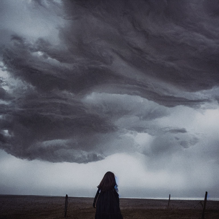 Solitary figure under stormy sky on desolate beach