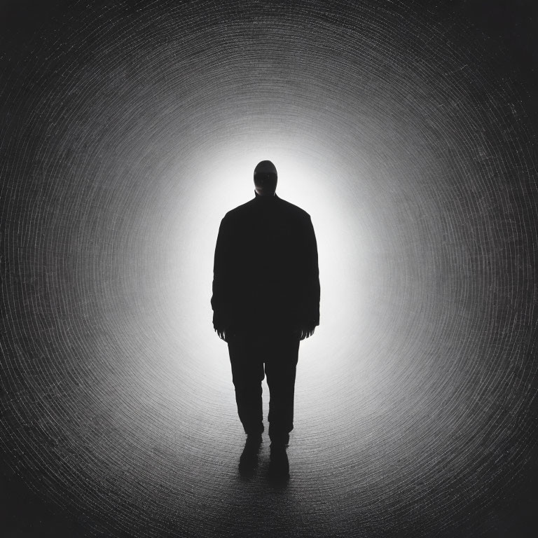 Person's Silhouette Against Bright Circular Light on Dark Textured Background