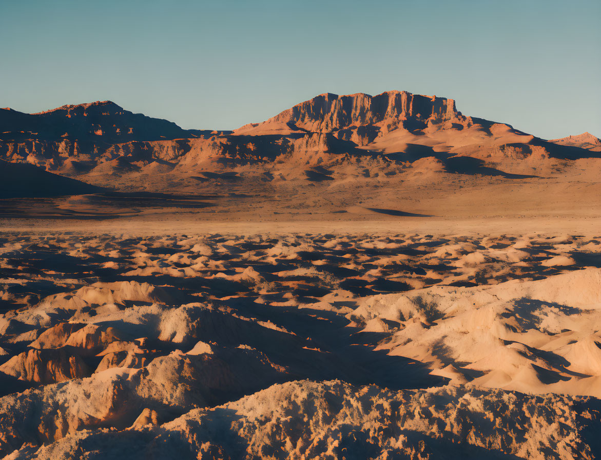 Arid Desert Landscape with Sandy Foreground and Mountain Plateau at Sunset