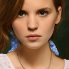 Young woman digital artwork: brown hair, blue eyes, beaded necklace, white blouse, contemplative