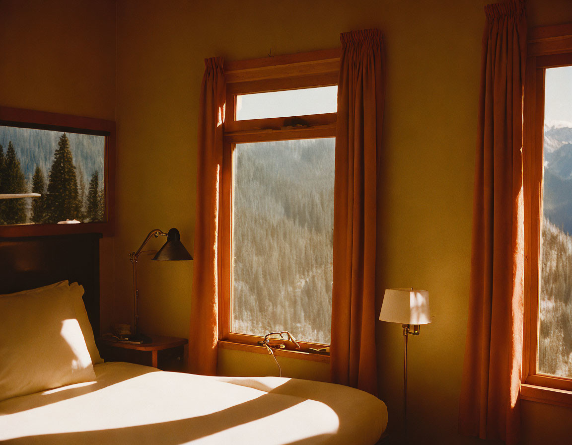 Warmly Lit Bedroom with Bed, Lamps, and Mountain Sunset View