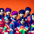 Eight individuals in colorful hair and futuristic outfits on orange backdrop