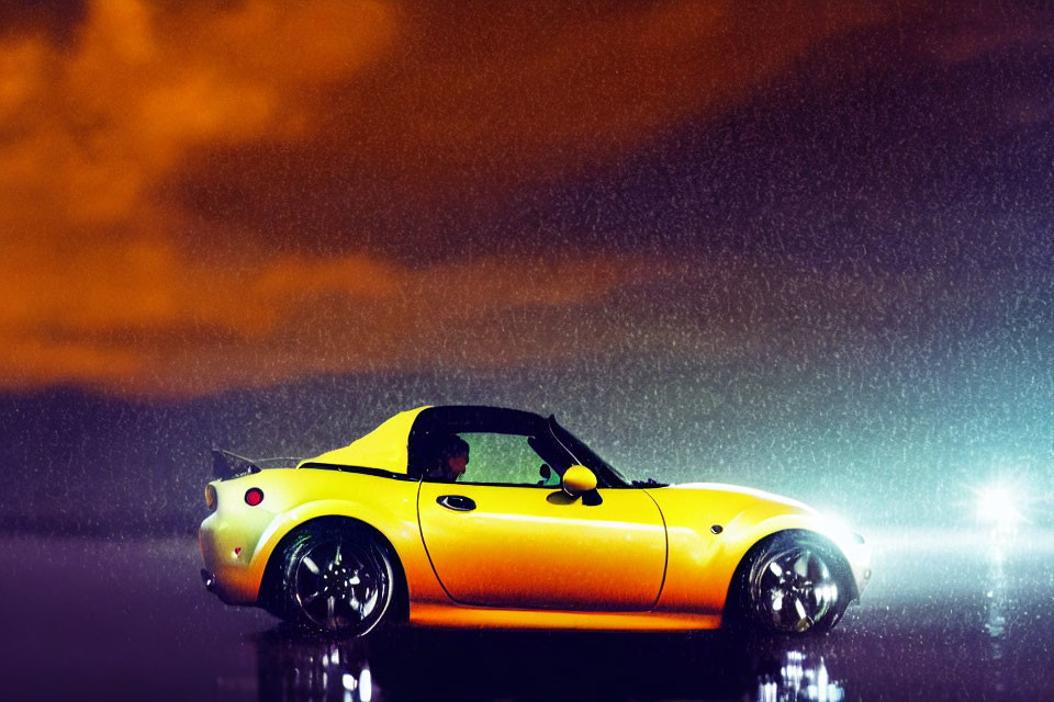 Yellow sports car parked at night in rain with headlights on, reflecting on wet ground under orange sky