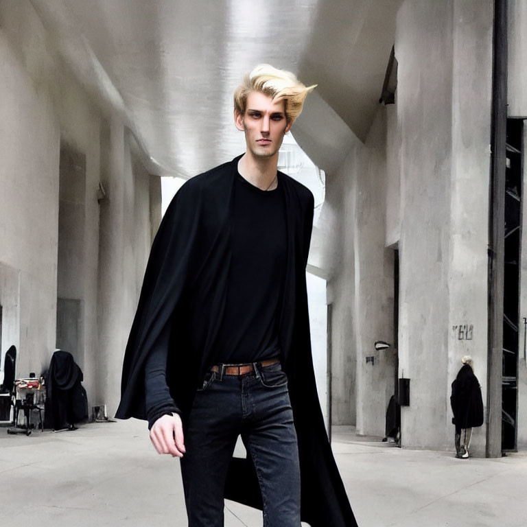 Blond man in black shirt and cape walking in modern structure