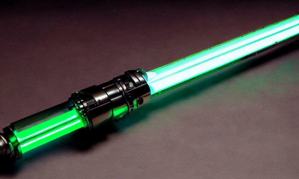 Green-bladed lightsaber with black hilt on dark surface