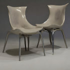 Two modern design chairs with sleek lines and glossy finish on grey background