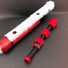 Red and White Sci-Fi Toy Swords with Black Grips on Black Surface