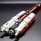 Futuristic white and black toy blaster with red LED lights on dark surface