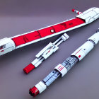 Three miniature spaceship models: red and white designs on grey surface