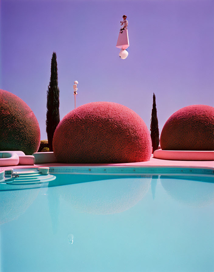 Surreal pink balls, small figure on a ball, cypress trees, blue pool, pink