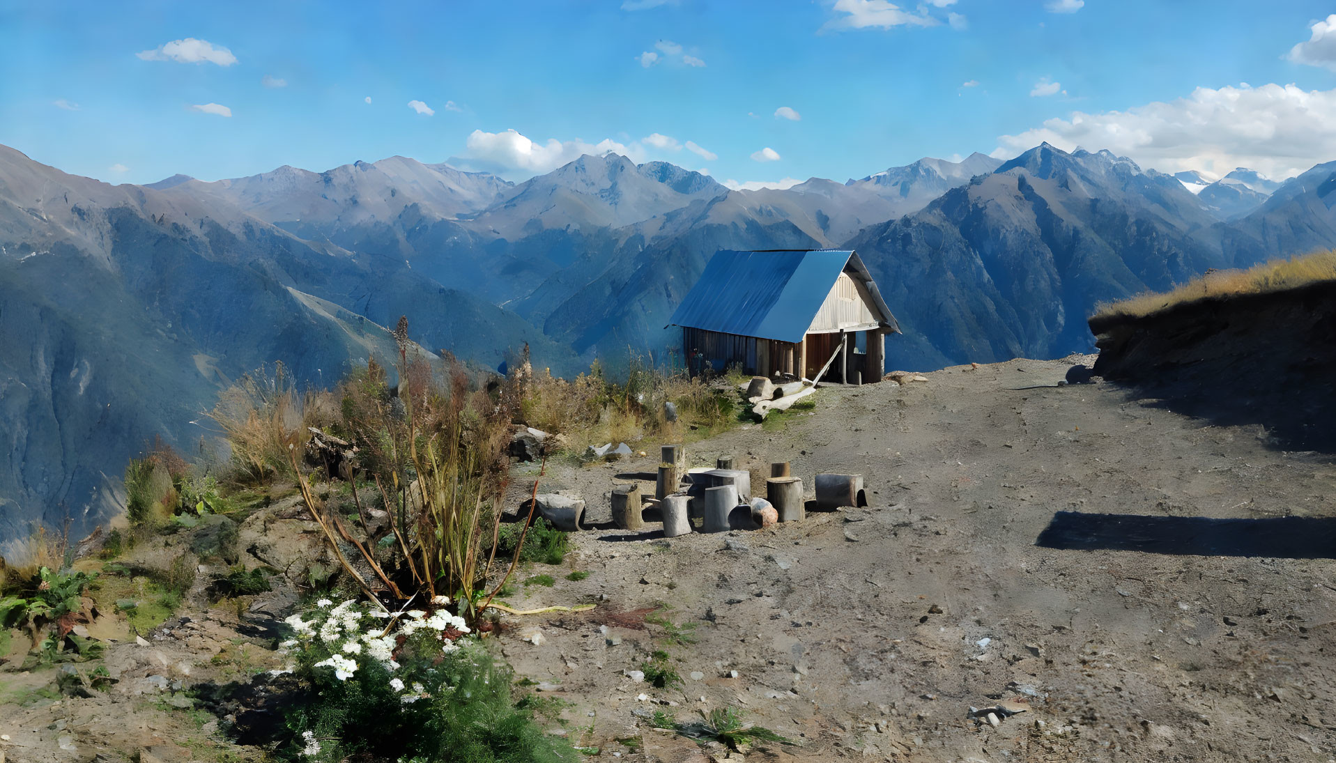 Mountain ridge cabin with blue roof and rugged peaks view