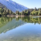 Tranquil mountain lake with pine trees and snowy peaks