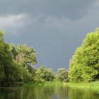 Tranquil river scene with lush green trees under cloudy sky