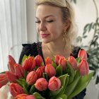 Young girl with braided hair and tiara holding colorful rose bouquet against botanical backdrop