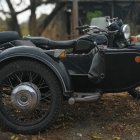 Vintage black motorcycle on autumn leaves with gleaming chrome details.